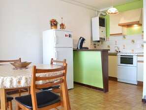A compact kitchen with a dining table, chairs, a refrigerator, a stove, and a sink. - 2-bedroom apartment, sleeps 6, air conditioning and parking in Banyuls (Banyuls-sur-Mer)