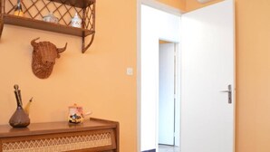 A room with a wooden dresser, a wall-mounted shelf with decorative items, and a white door leading to another room. - 2-bedroom apartment, sleeps 6, air conditioning and parking in Banyuls (Banyuls-sur-Mer)
