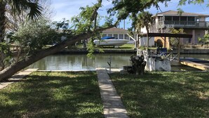 Une propriété située au bord de l’eau, dotée d’un quai, d’un bateau et d’une maison avec un balcon donnant sur l’eau.