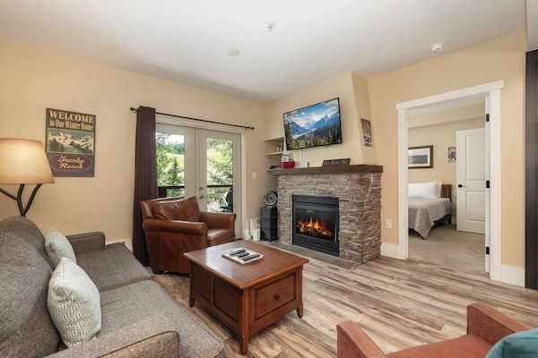 Open concept kitchen, dining and living area with gas fireplace, flat screen TV, pull-out sofa and views of the slope