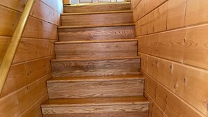 A wooden staircase with a handrail, leading upwards.