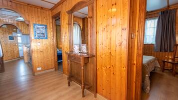Ein Zimmer mit Holzwänden, einem Bett, einer Holzkommode und einem Spiegel.