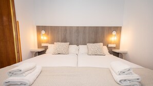 Un lit double avec deux oreillers, une tête de lit en bois et deux tables de chevet avec des lampes.