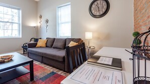 A living room with a sofa, a coffee table, a lamp, a clock, and a window. - Amazing historic home from 1860!  (St Charles)
