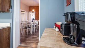 A modern kitchen with a coffee maker, a dining area with chairs, and a wooden floor. - Amazing historic home from 1860!  (St Charles)