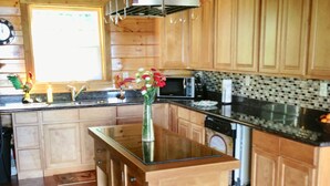 A kitchen with wooden cabinets, a central island with a vase, and a microwave. - Spectacular Views, Swimming Pool, Hot Tub, Real Log Fires, Mountain Getaway (Rileyville)