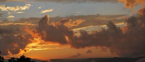 Un atardecer sobre un paisaje montañoso con nubes.