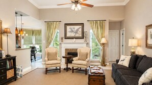 A spacious living room with a ceiling fan, a fireplace, and a view of the outdoors. - Centrally Located- 2 mi. North of downtown OS with screened porch, full kitchen (Ocean Springs)