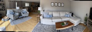 Uma sala de estar moderna com um sofá modular cinzento, poltronas estampadas e uma mesa de centro.