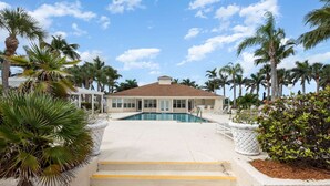 Un resort con piscina, palmeras y un edificio de techo marrón.