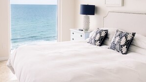 A bedroom with a large bed, a ceiling fan, a nightstand with a lamp, and a view of the ocean. - Newly Renovated Gulf Front Gorgeous Views in St. Maarten from the 10th floor!  (Destin)