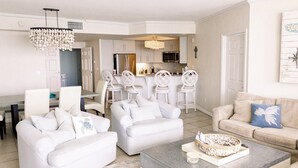 A modern living room with white furniture, a dining area, and a kitchen with white cabinets and stainless steel appliances. - Newly Renovated Gulf Front Gorgeous Views in St. Maarten from the 10th floor!  (Destin)