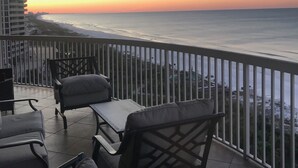 A balcony with a view of the ocean at sunset, featuring outdoor furniture and a railing. - Newly Renovated Gulf Front Gorgeous Views in St. Maarten from the 10th floor!  (Destin)