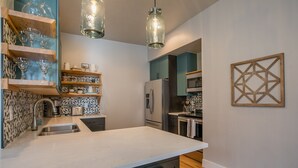 A modern kitchen with a large island, built-in appliances, and decorative shelves. - Family Friendly Modern Historic Luxury, Minutes to Walk to CSU and Old Town!  (Fort Collins)
