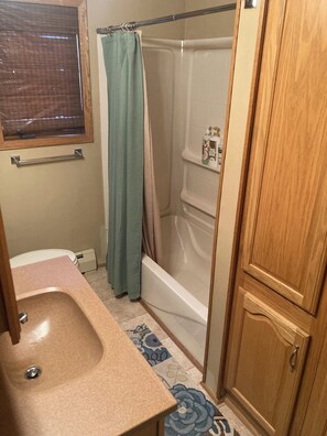 Un baño con lavabo, ducha, inodoro y un armario.