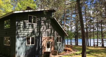 Northwoods lake home with gentle slope to clear lake with sandy beach