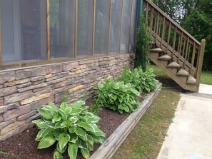 Pared exterior de piedra con una escalera de madera que lleva a una puerta.