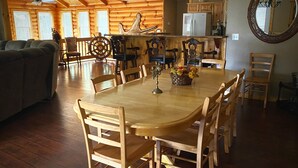 A wooden dining table with chairs, a chandelier, and a kitchen area with wooden cabinets and a refrigerator. - Great for family vacations, weddings, And Church retreats.  (Fort Payne)
