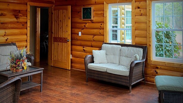 A log cabin interior with a wooden balcony, wicker furniture, and a mounted animal head. - Great for family vacations, weddings, And Church retreats.  (Fort Payne)