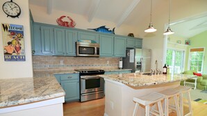 A kitchen with teal cabinets, a granite countertop, stainless steel appliances, and a central island with bar stools. - 4 Bedroom, Community Pool!  517 Doral Drive, Bethany West (Bethany Beach)