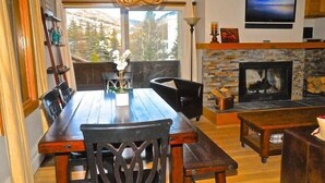 A dining area with a wooden table and chairs, a fireplace, and a television mounted on the wall.