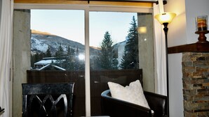 A room with a large window, a chair, a table, and a lamp.