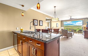 Een moderne keuken met een groot eiland, een eethoek met uitzicht en een woonkamer met een groot raam.