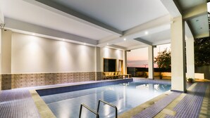 A large indoor swimming pool with clear water, surrounded by tiled flooring and walls, and a few chairs near the pool's edge. - D'Polo Club And Spa Resort, Dharamshala (Dharamshala)