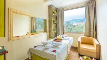 Relax in a spacious room with a large bed, sitting area, and window offering a view of the outdoors.
