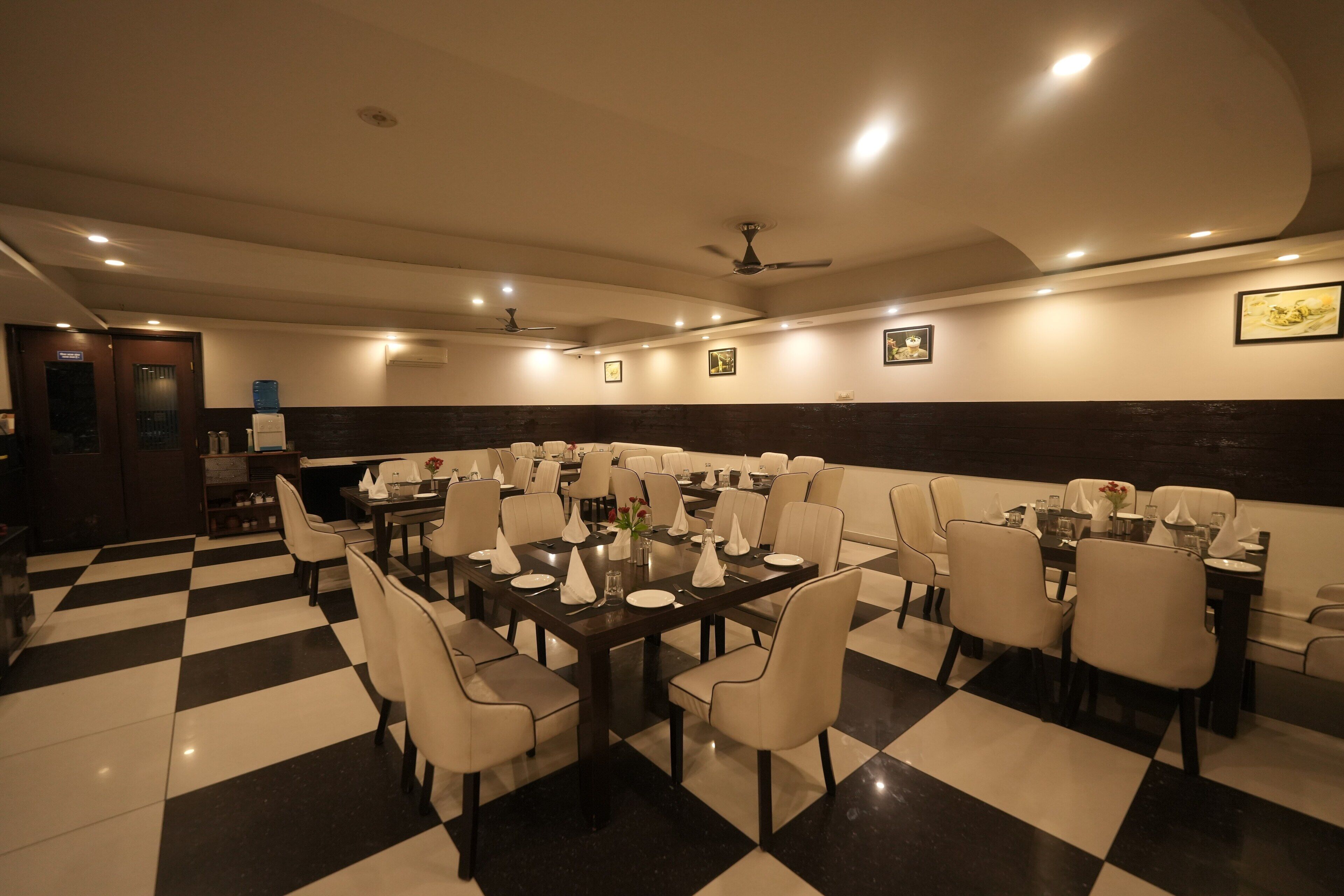 A restaurant with a checkered floor, multiple dining tables, and chairs.