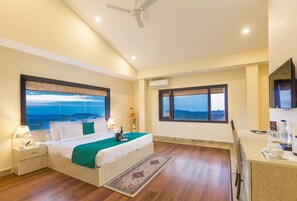 Une chambre avec un grand lit, un bureau et une vue sur le paysage.