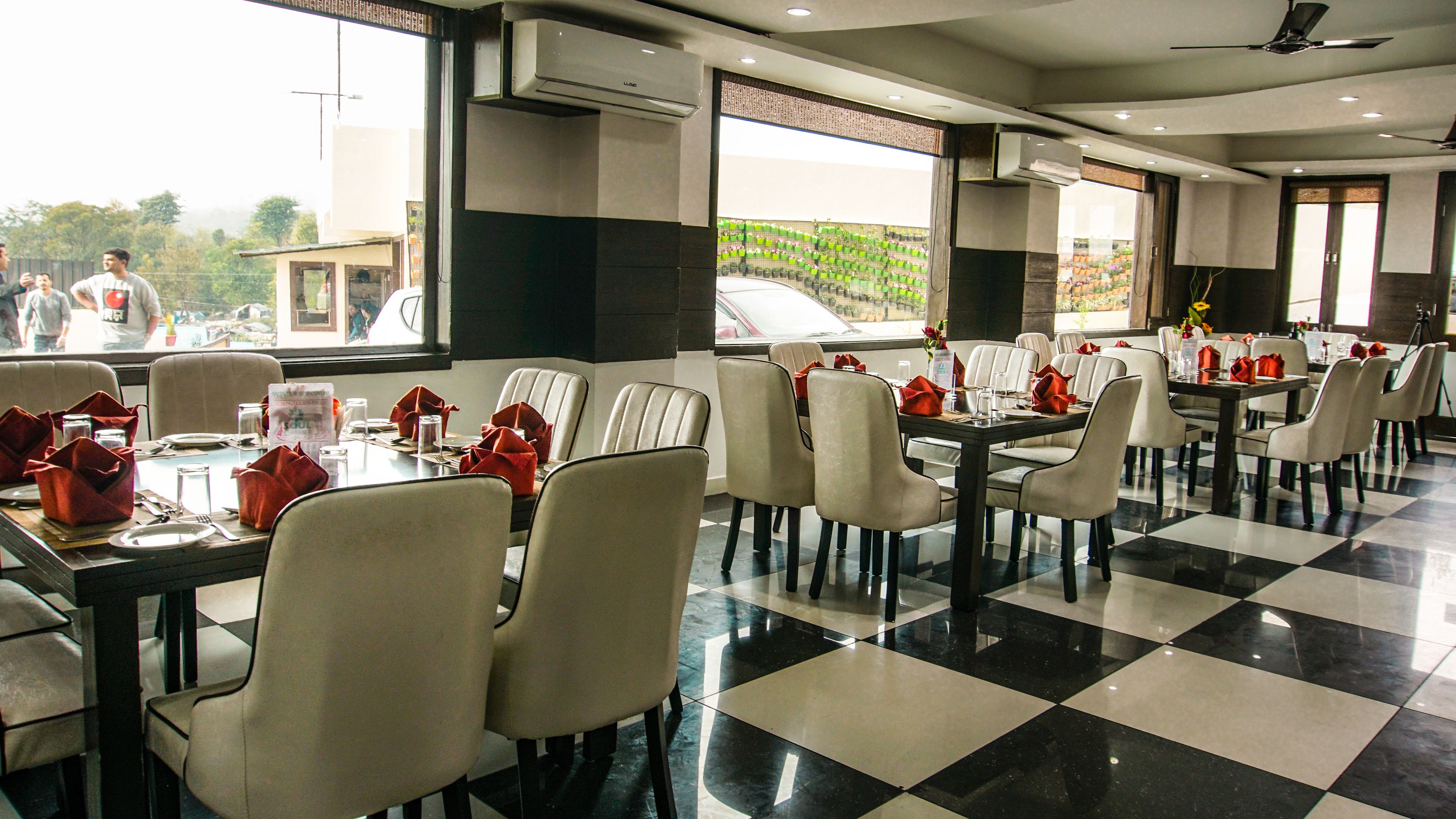 Un restaurant avec un sol à carreaux, des murs blancs et noirs, et une vue sur l’extérieur.