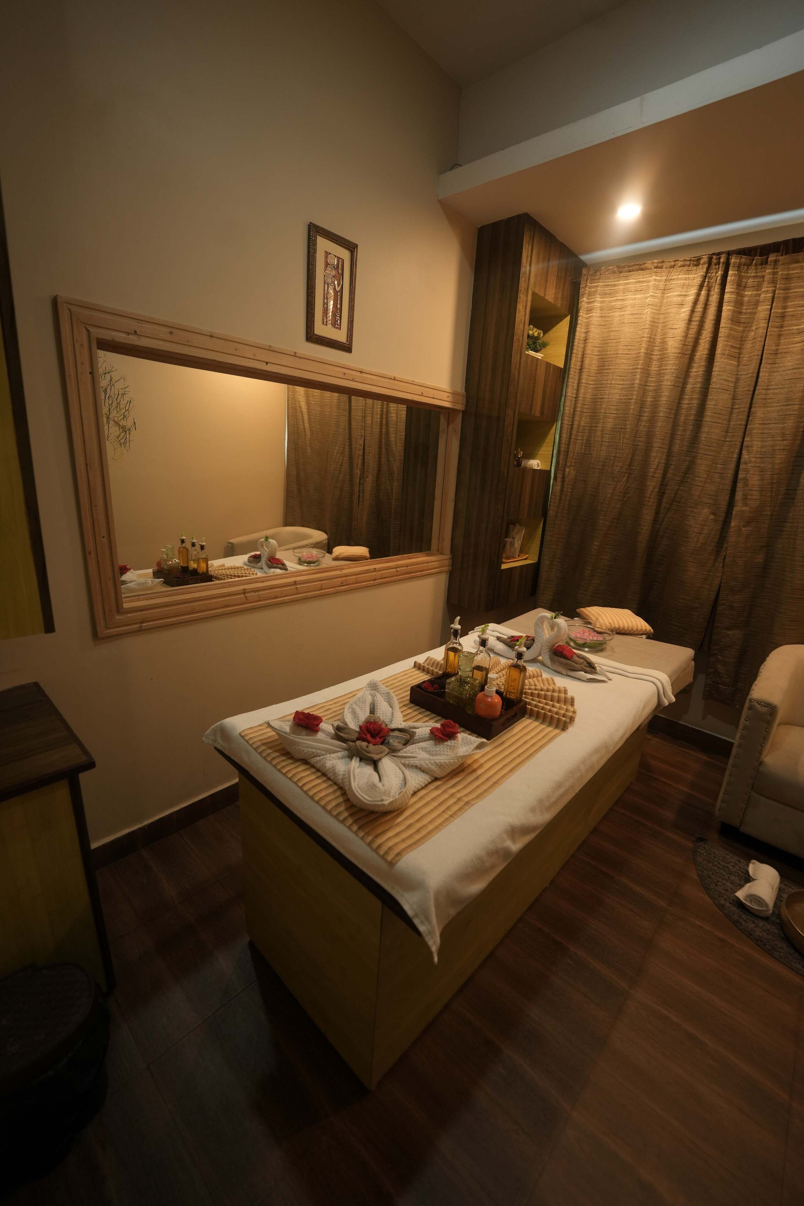 A hotel room with a large bed, a bedside table, a mirror, and a window with curtains.