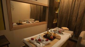 A hotel room with a large bed, a bedside table, a mirror, and a window with curtains.