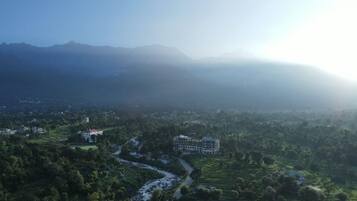 A mountainous landscape with a river, buildings, and greenery.