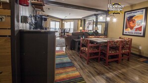 A spacious living area with a wooden dining table and chairs, a sofa, and a large window offering a view. - Seven Springs Slope-Side Home, Ski right to the Lift #1  Boomerang Trail. (Champion)