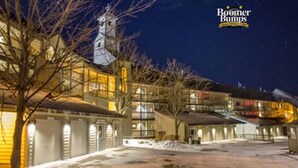 A hotel with multiple buildings, a bell tower, and a snow-covered ground. - Seven Springs Slope-Side Home, Ski right to the Lift #1  Boomerang Trail. (Champion)
