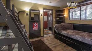 A compact room with a bunk bed, a ski patrol sign, a small closet, and a window with blinds.