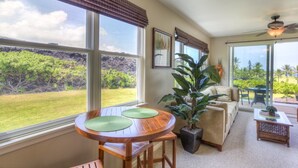 Un salón amplio con una mesa de madera, un sofá y un ventanal que ofrece vistas a un jardín exuberante.