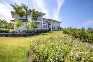 A two-story house with a balcony, surrounded by a well-maintained lawn and flowering plants. - Aloha Condos, Na Hale O Keauhou, Townhome K-2, Ocean View, AC (Kailua Kona)