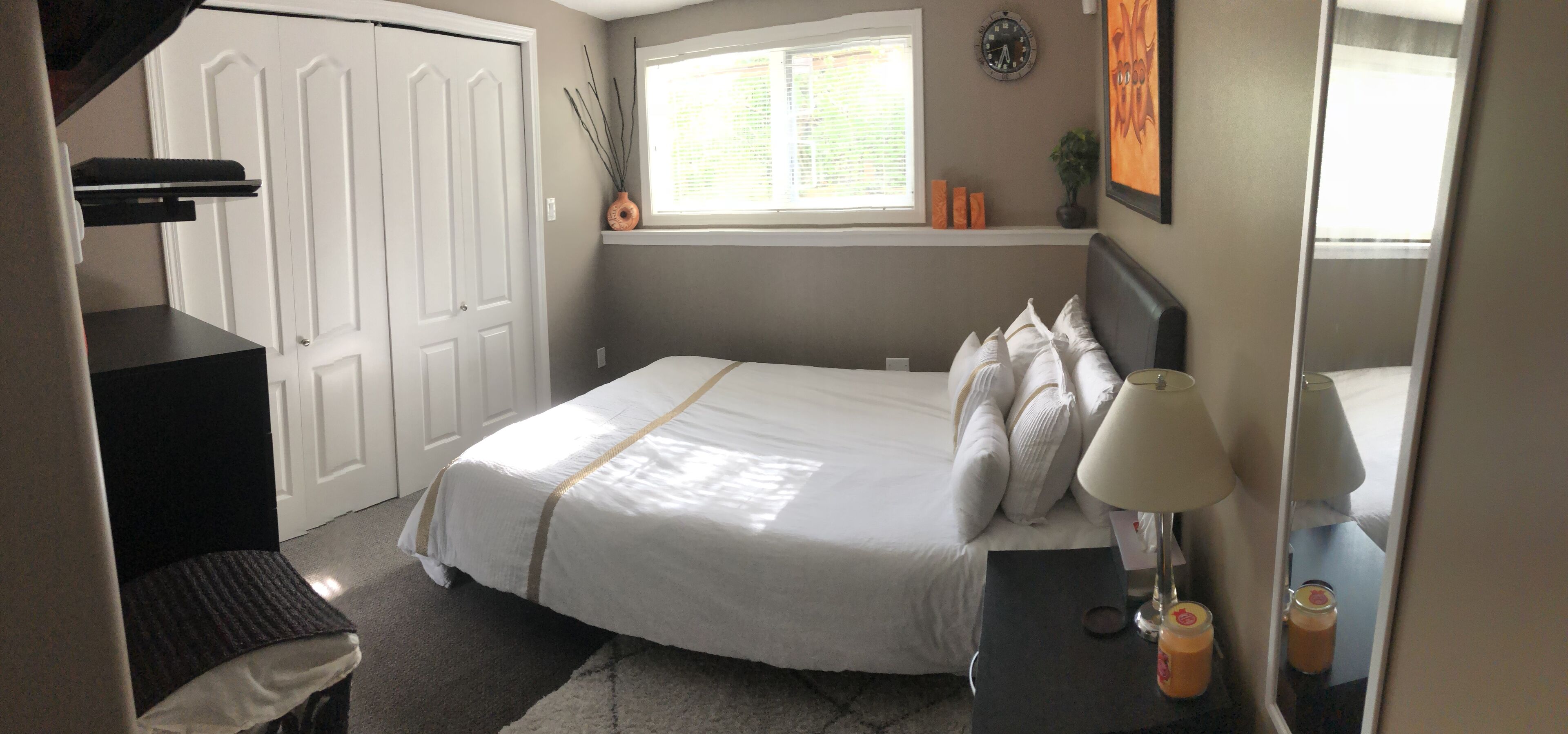 A bedroom with a bed, bedside table, lamp, and a window with blinds.