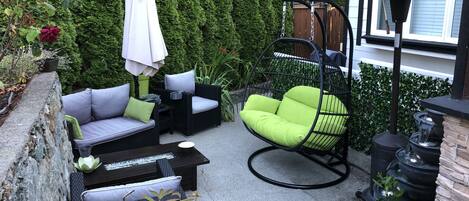 A patio with outdoor furniture, a hanging chair, and a water feature.