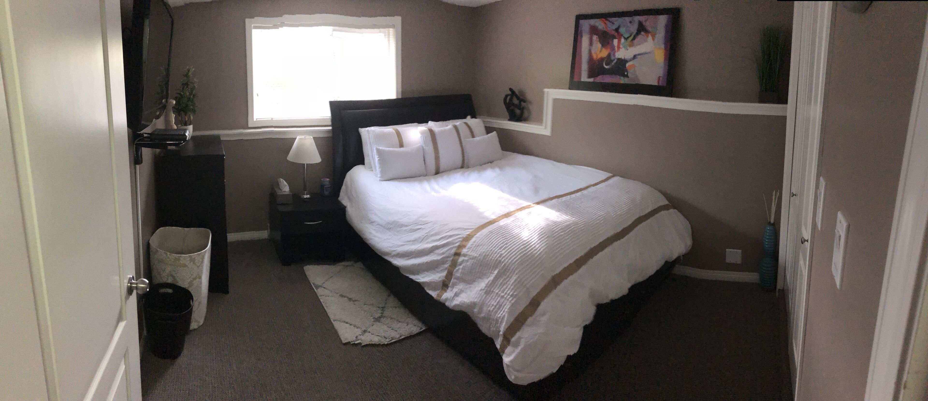 Un dormitorio con cama, mesita de noche, lámpara y ventana.