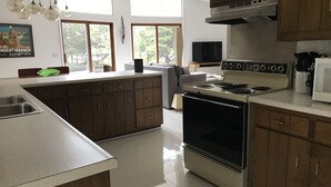 A modern kitchen with a central island, stainless steel appliances, and large windows.
