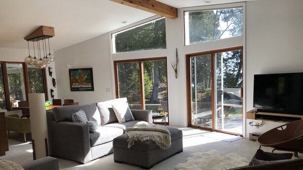 A modern living room with a grey sofa, a white furry rug, and a brown chair.