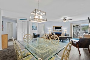 Relax in a spacious living area with a dining table, sofa, and armchairs, plus a large window offering a view of the outdoors.