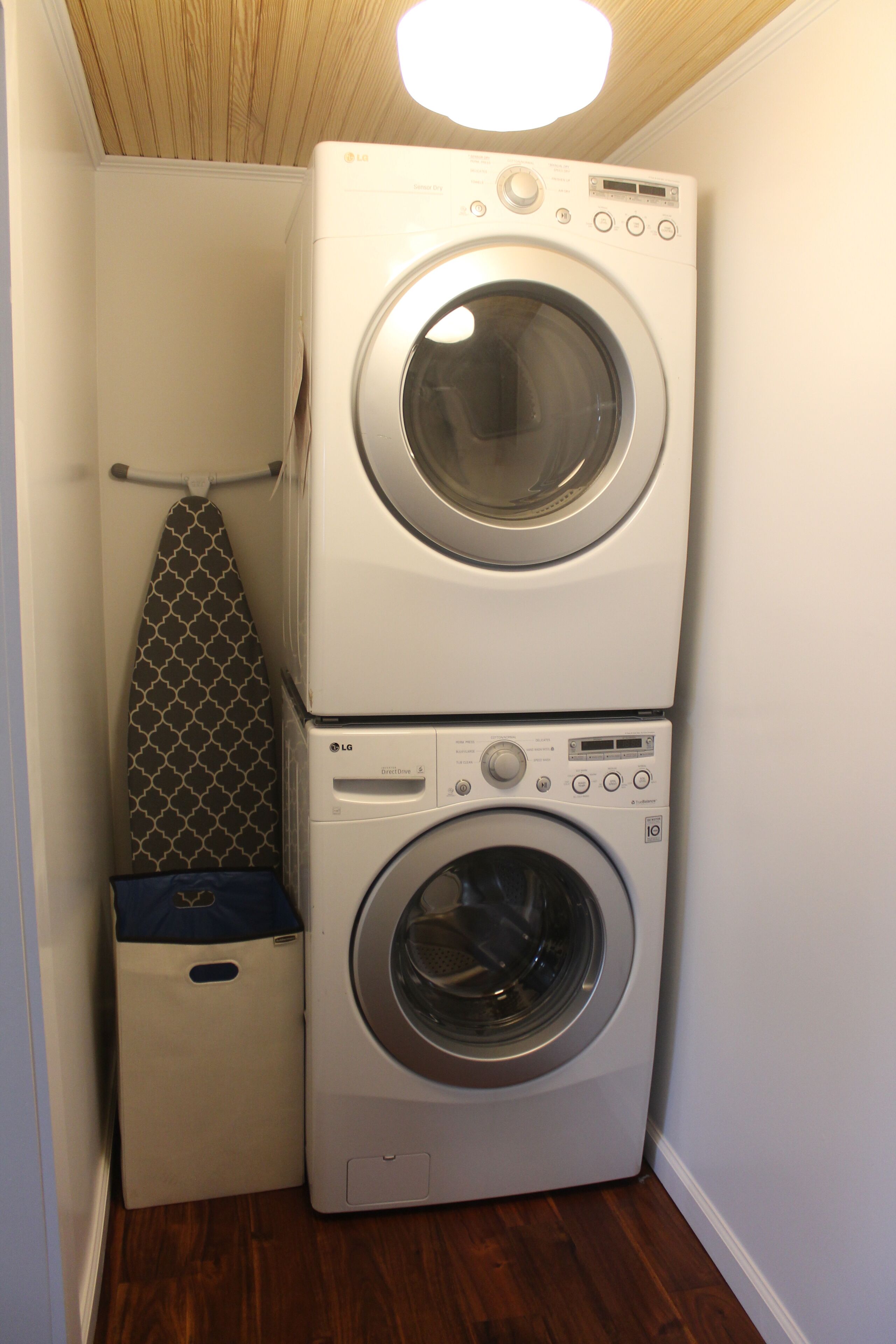 A laundry room with two stacked washing machines and a drying rack.