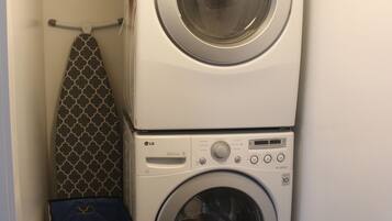 A laundry room with two stacked washing machines and a drying rack.