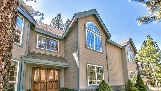 A two-story house with a front entrance, large windows, and a brick foundation. - Huge 7BR/4.5BA - Hot Tub, Ping Pong/Pool Table, Arcade, Gas BBQ (South Lake Tahoe)
