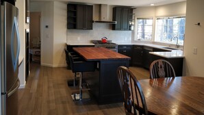 A modern kitchen with dark cabinets, a wooden island, and a large window providing natural light. - Huge 7BR/4.5BA - Hot Tub, Ping Pong/Pool Table, Arcade, Gas BBQ (South Lake Tahoe)
